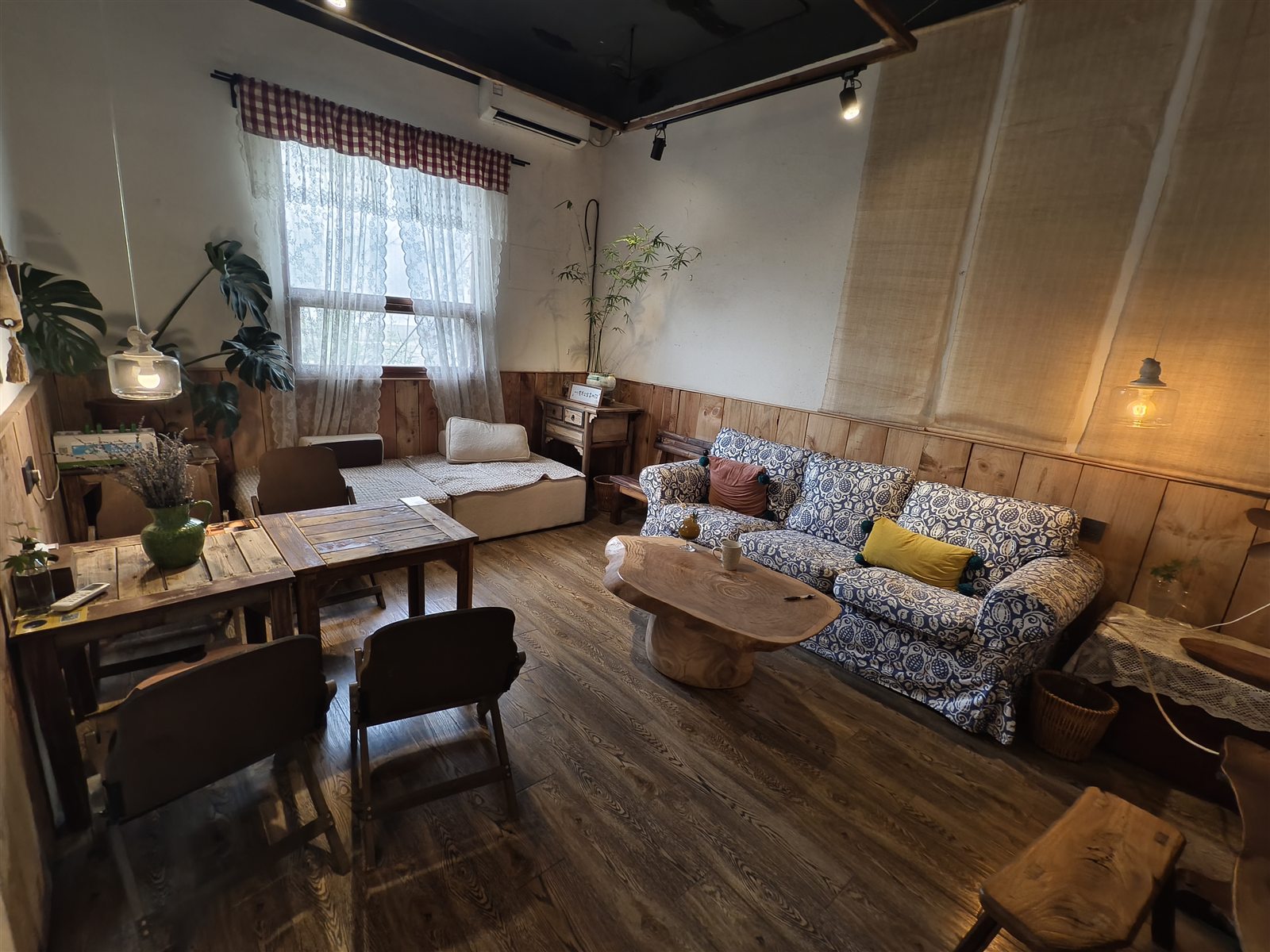 鸟屋咖啡里铺着花纹布艺的沙发、旧木桌和窗边坐席