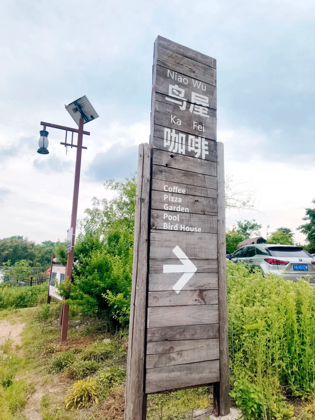 乡间路口写着鸟屋咖啡和向右箭头的木牌